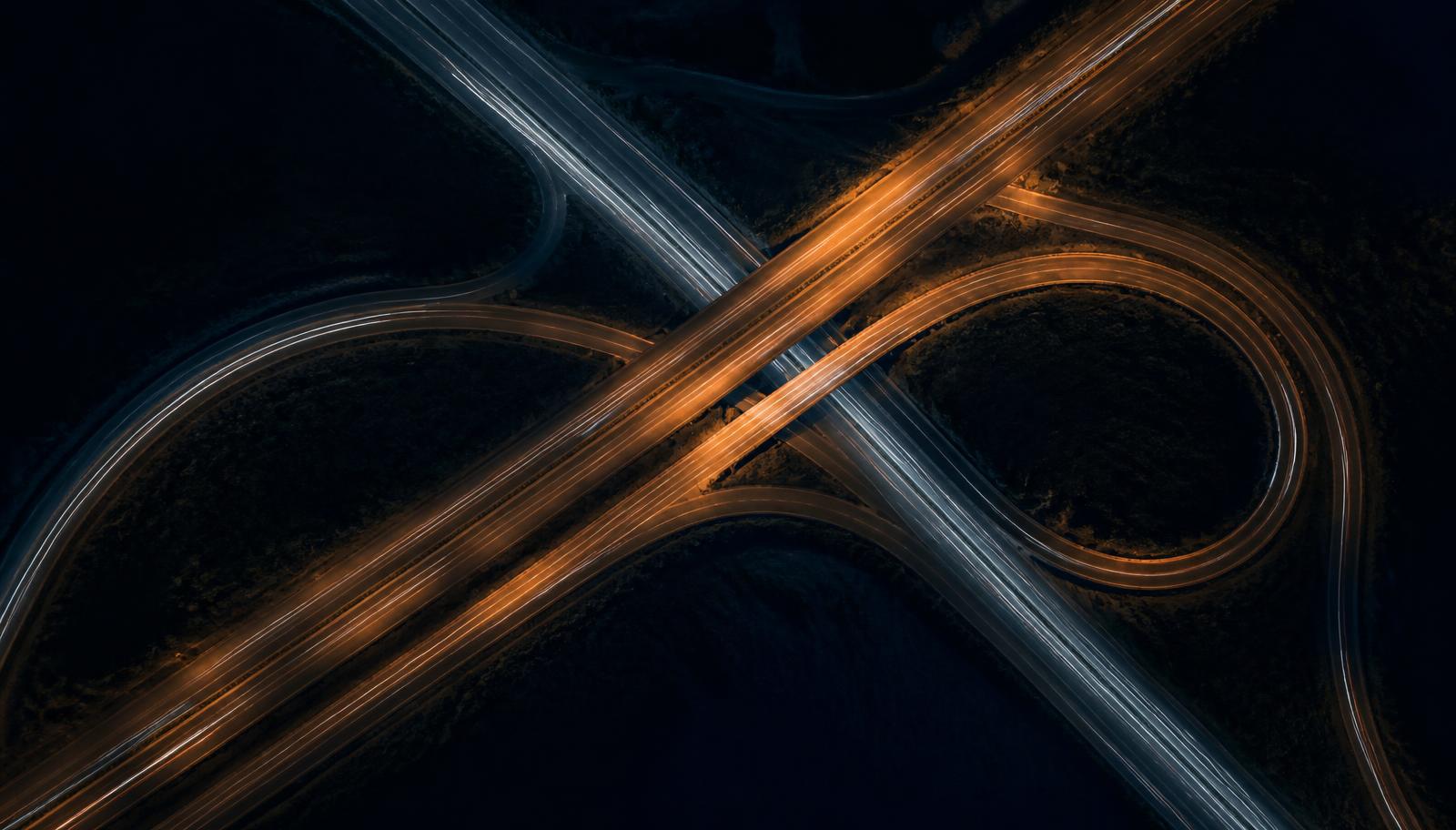 Vue aerienne nocturne d'un echangeur autoroutier avec trainees lumineuses